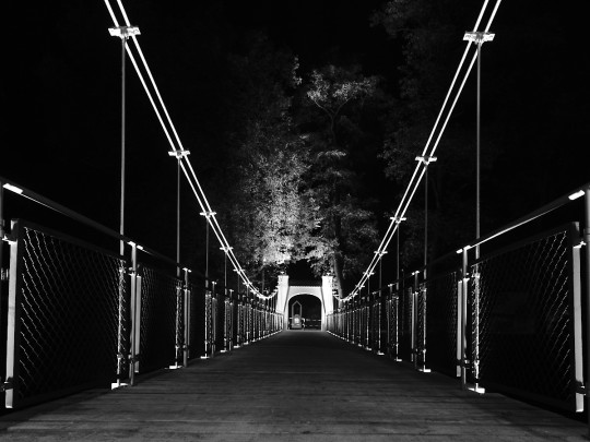 Most wiszący nocą, oświetlony iluminacją.