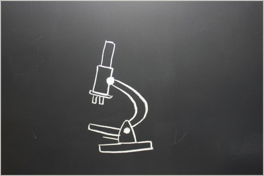 Rysunek białą kredą mikroskopu, na czarnej ścianie.