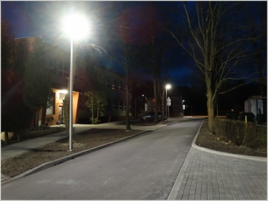 Widok na drogę asfaltową w nocy, która jest oświetlona lampą uliczną.
